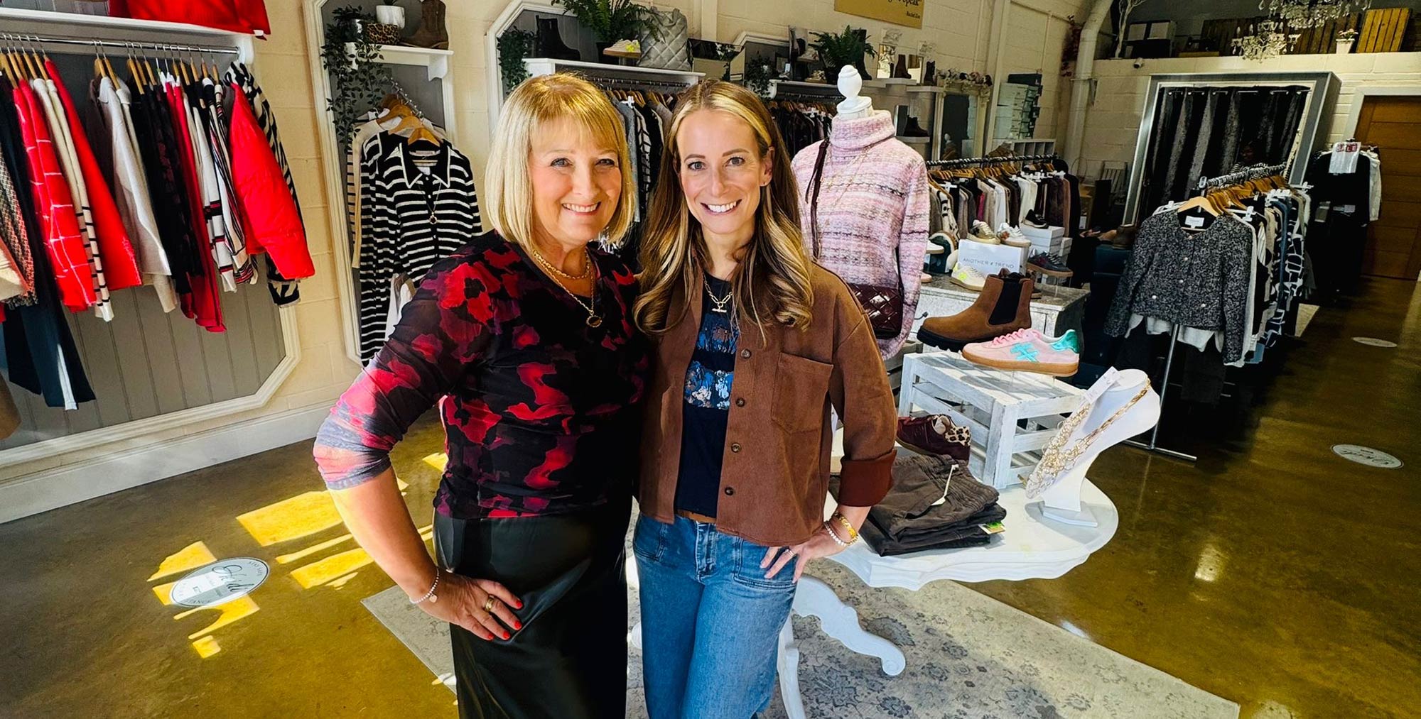 julie and heidi standing in store with racks of clothes and mannequins in the background.