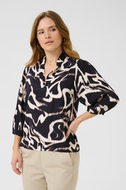 Woman wearing a patterned blouse with rolled-up sleeves on a white background