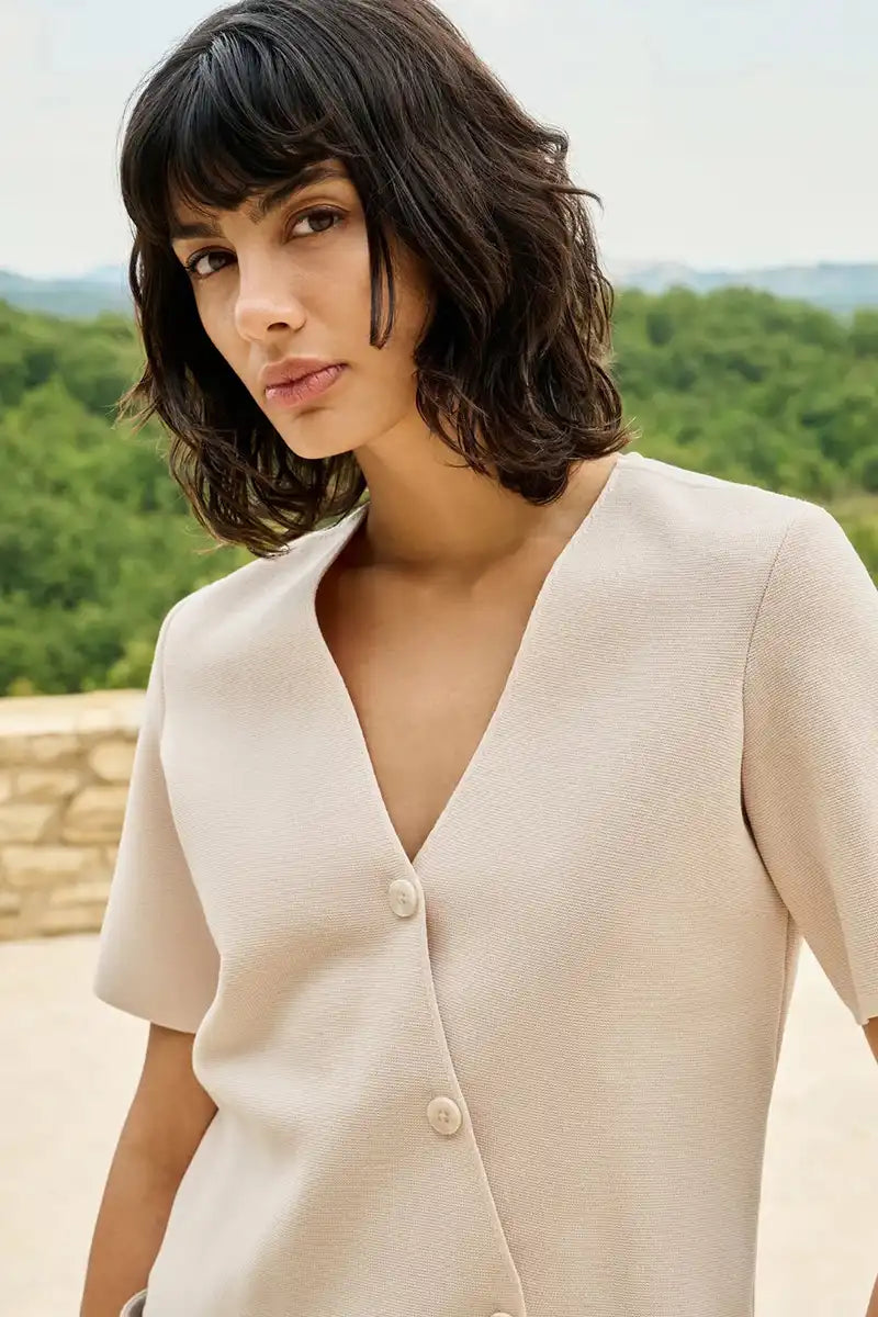 Woman wearing a beige cardigan with a scenic background