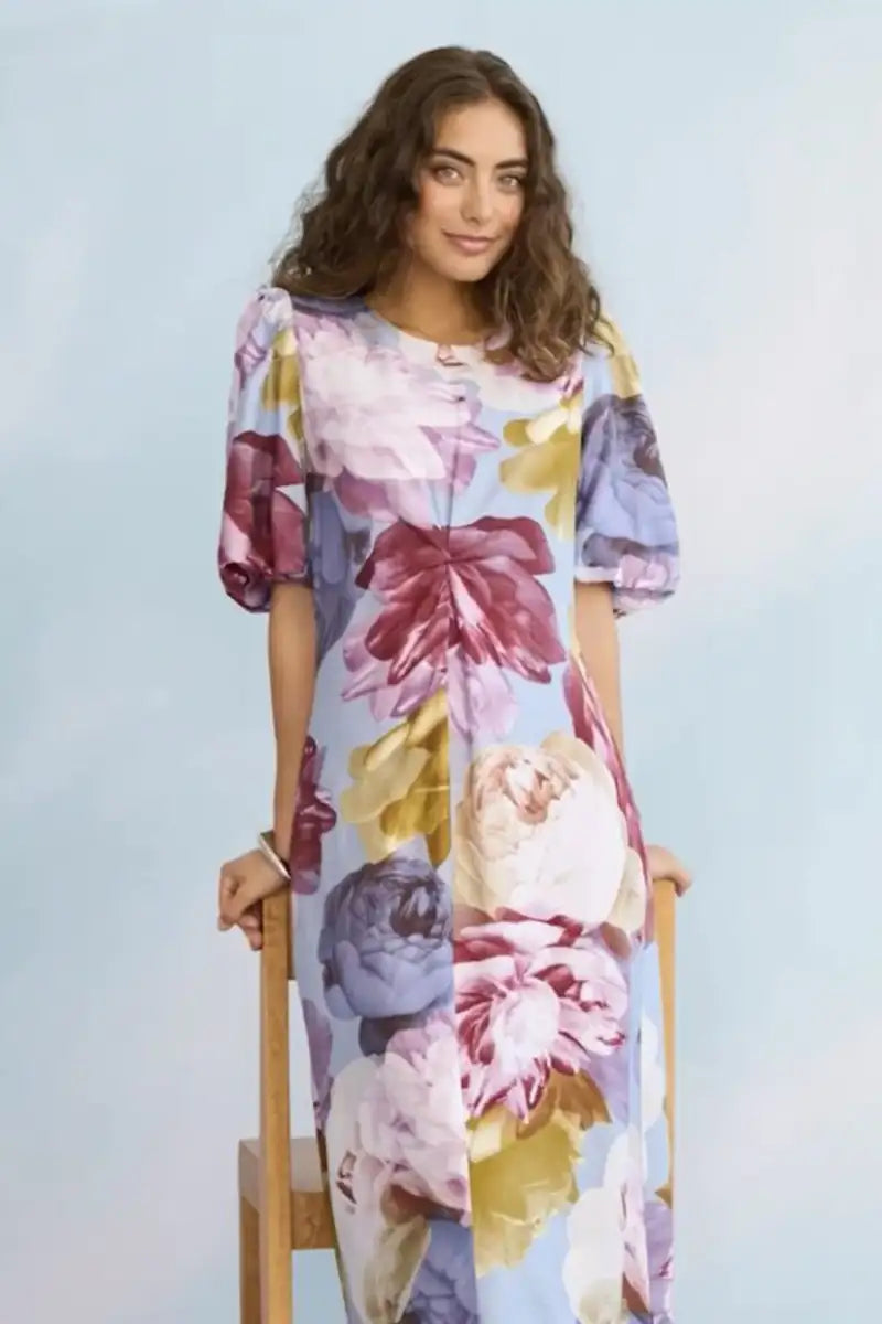 Woman wearing a colorful floral dress against a light blue background